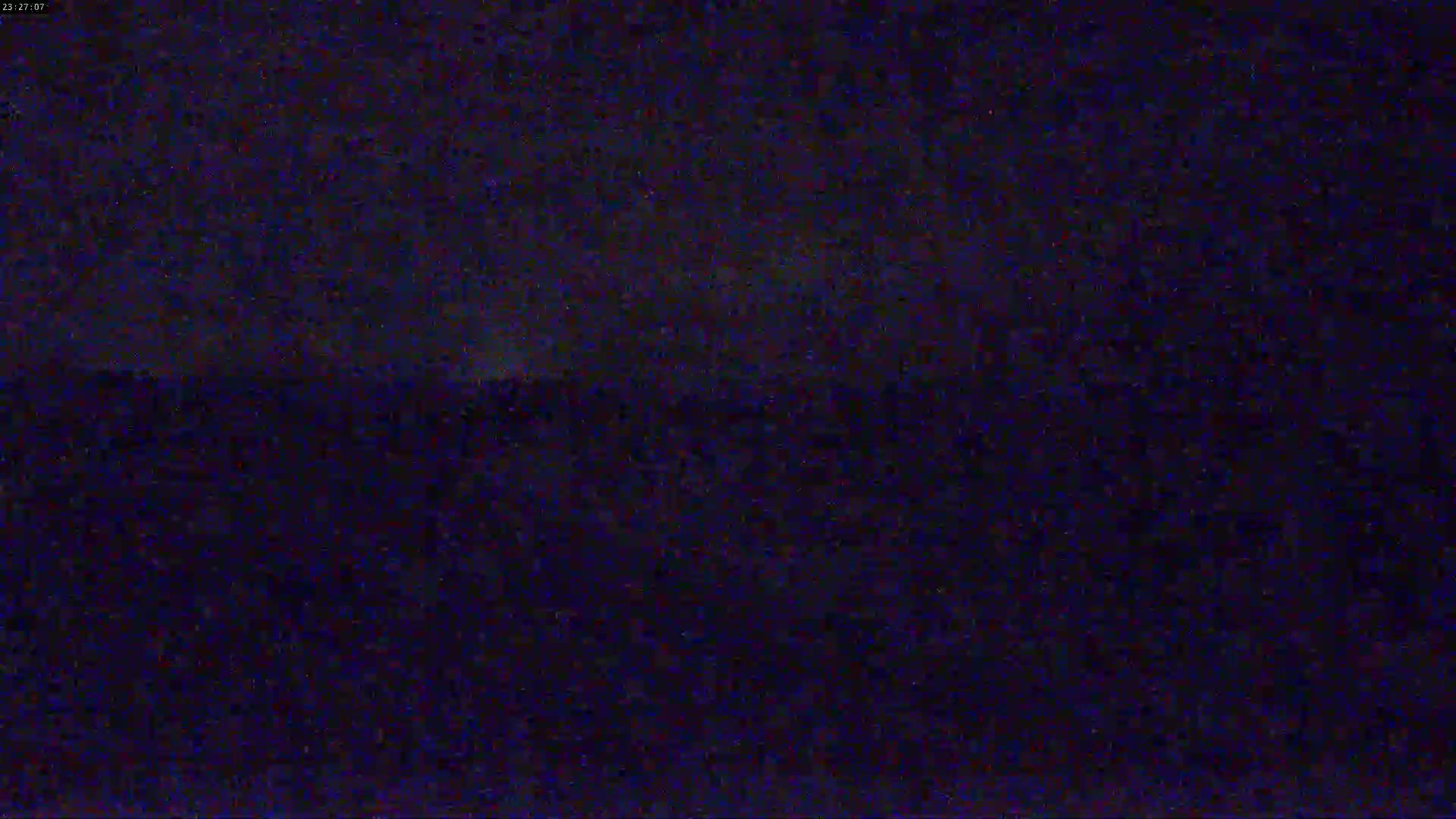 A dark, nighttime scene shows a blurry, indistinct landscape under a mostly clear sky.