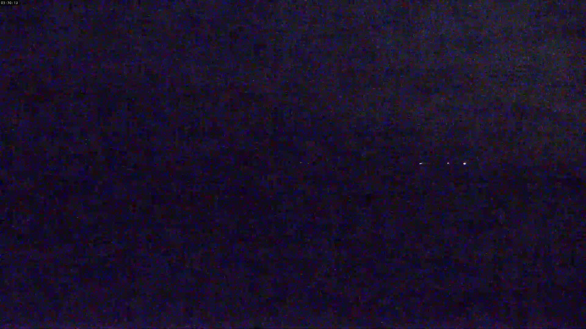 A nighttime image shows a dark, possibly overcast sky with a few faint lights visible in the distance.