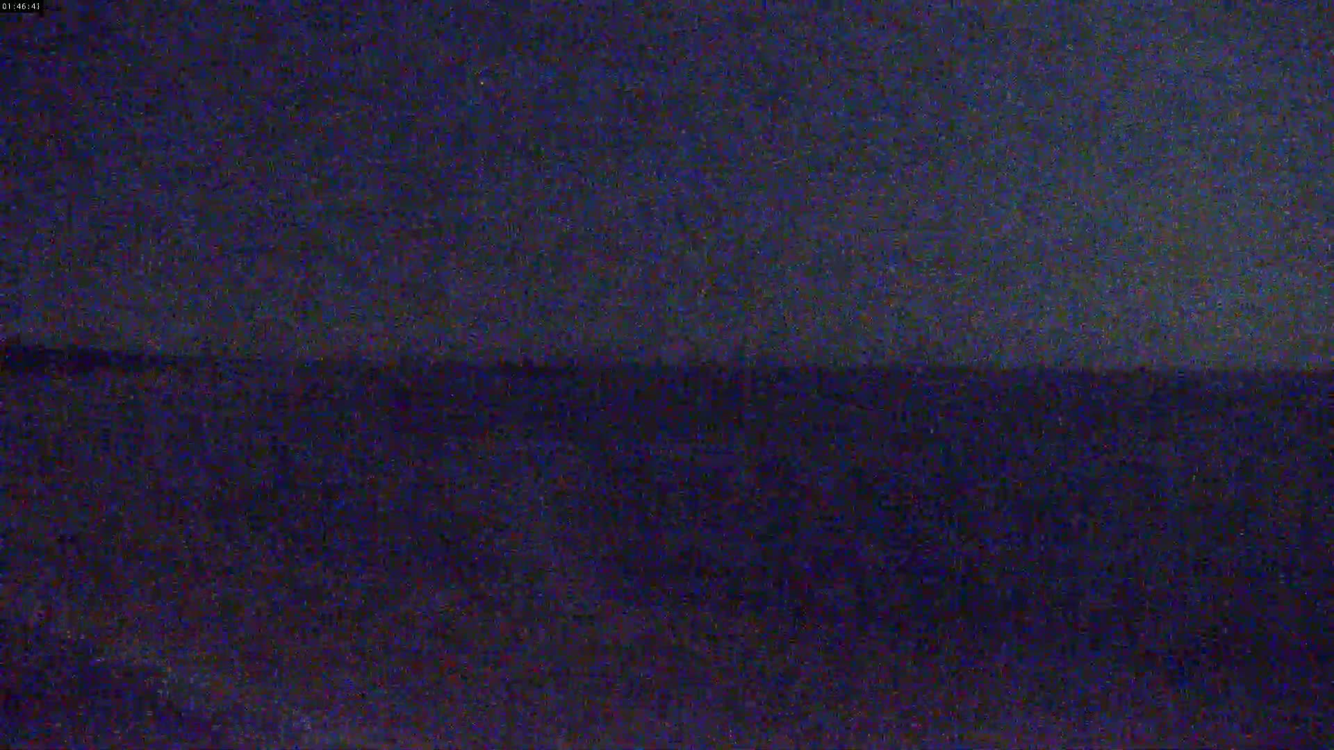 A dark, nighttime outdoor scene shows a blurry, indistinct landscape under a dark sky.