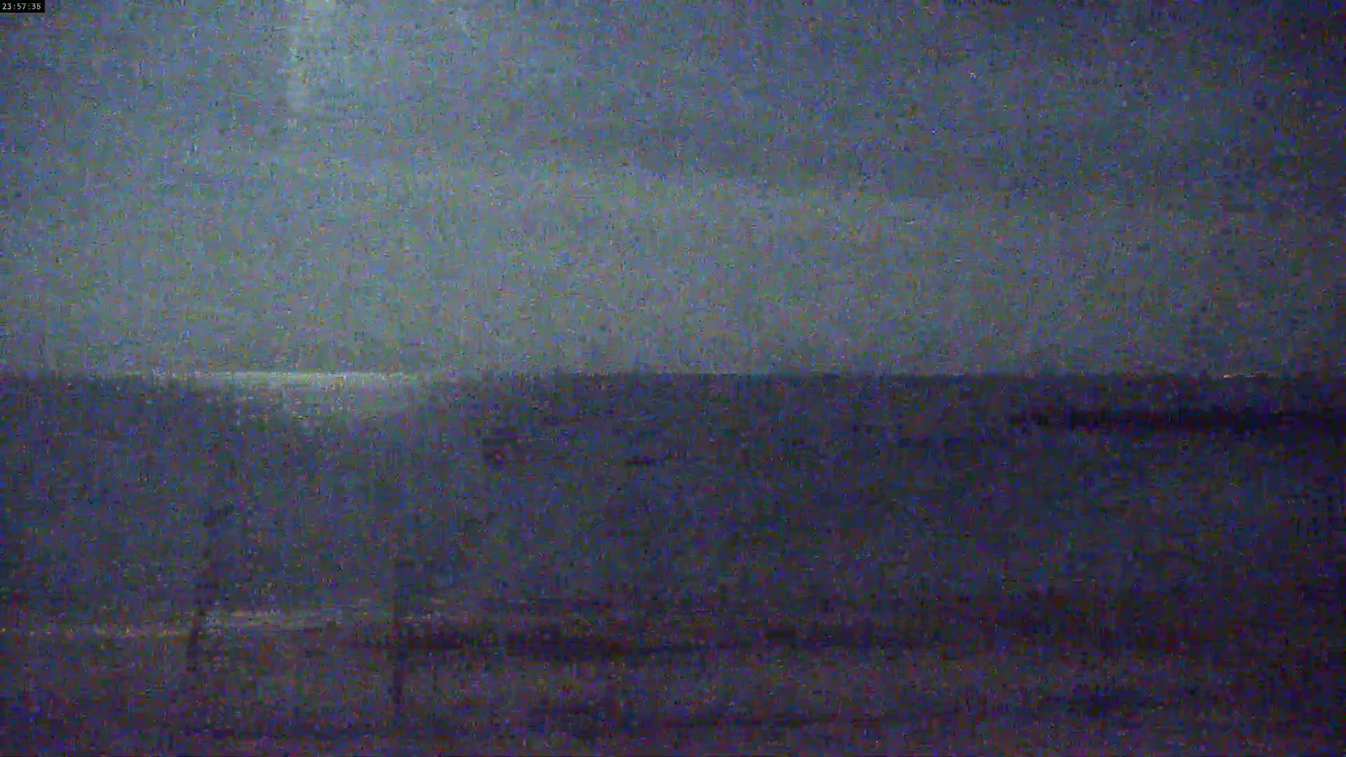 A dark, blurry image shows a body of water under a dusky sky at night.