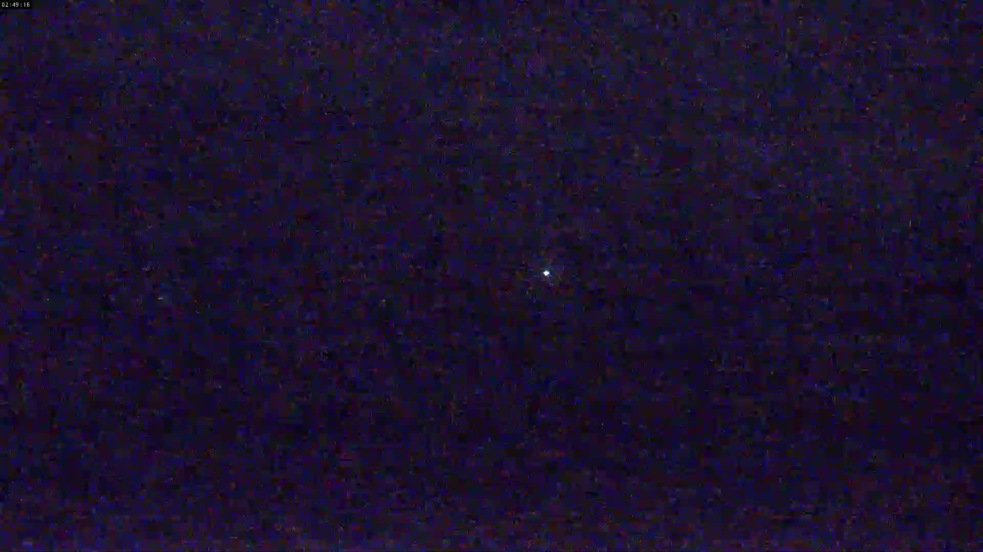 A single, bright light is visible in a dark, nighttime sky.