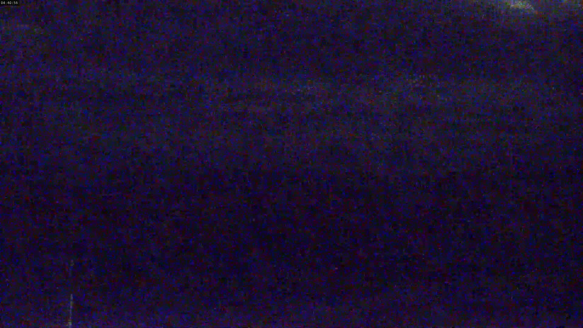A dark, grainy image shows a mostly uniform dark blue-purple surface.