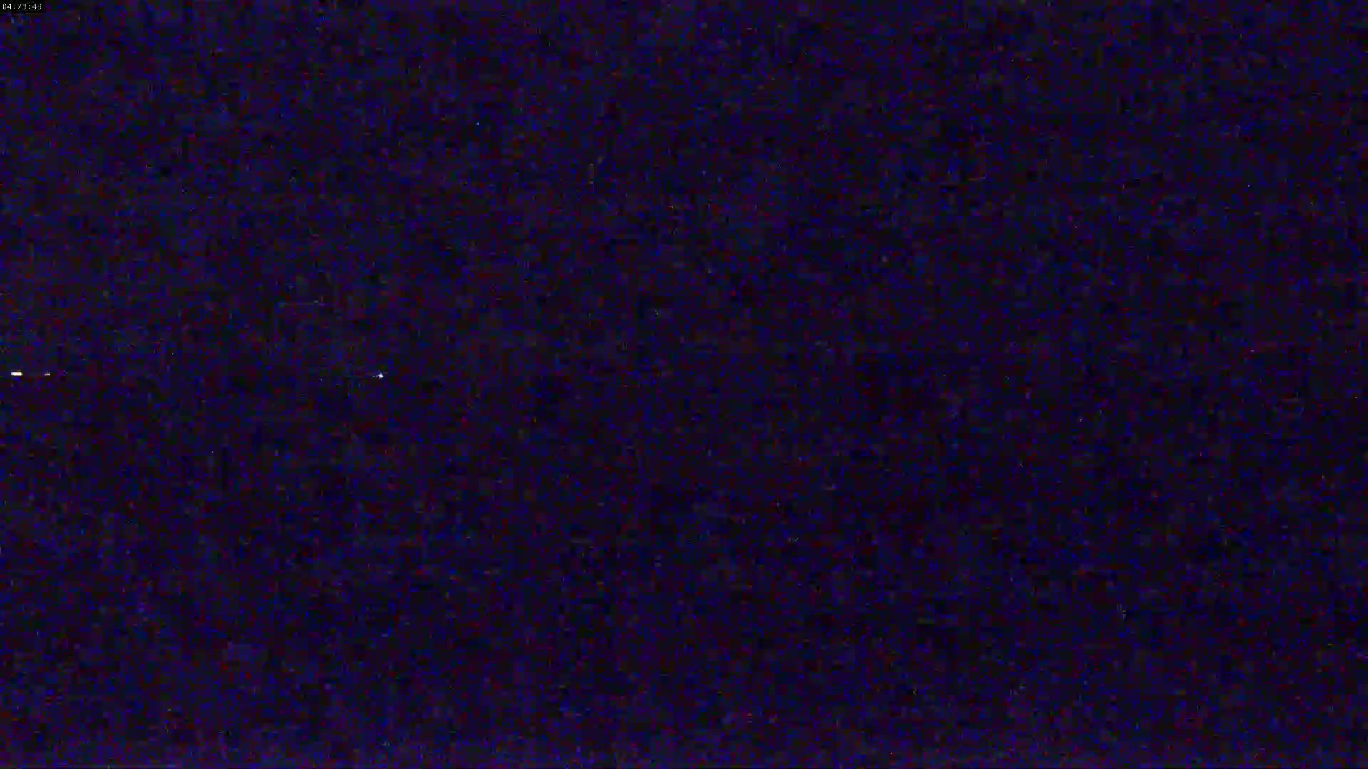 A dark, possibly nighttime image shows a heavily pixelated or static-filled view with a few faint bright spots.