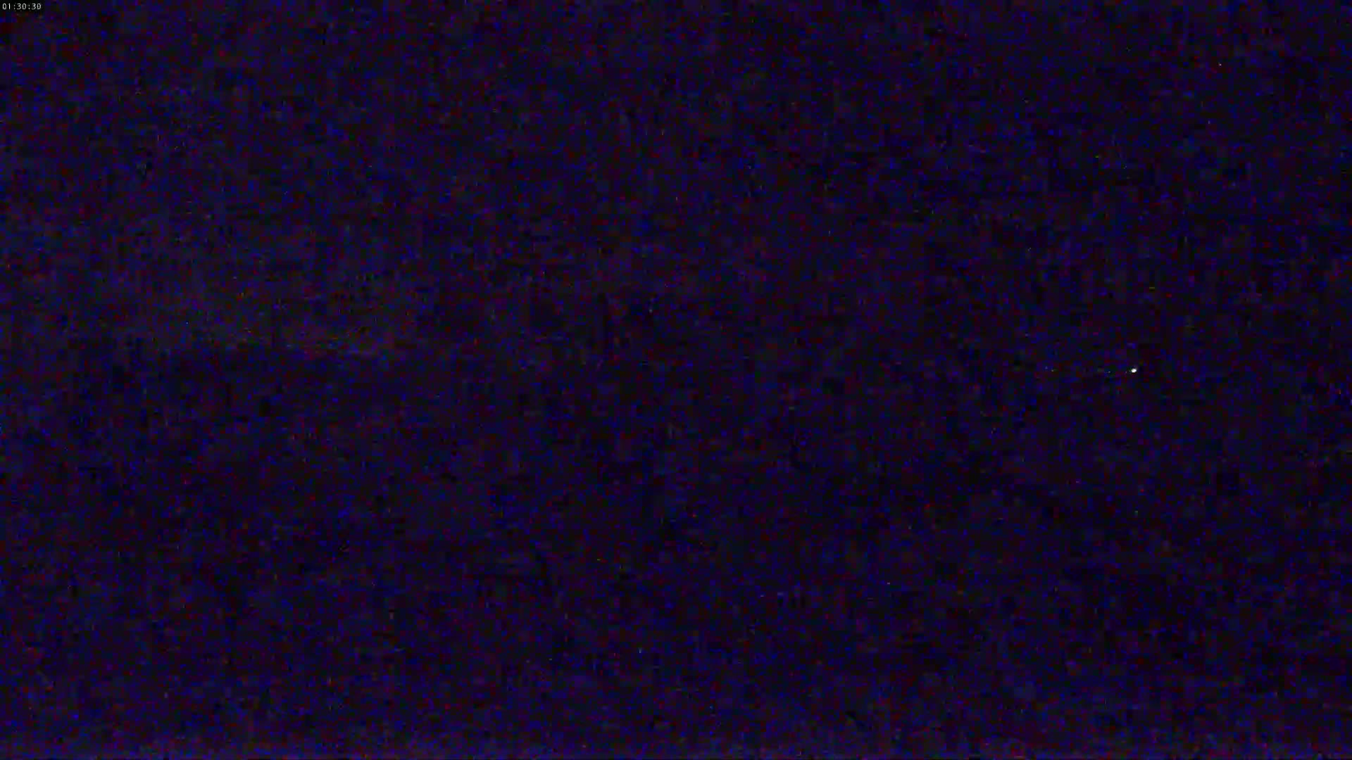 A dark, nighttime scene shows a mostly clear sky with a few faint, distant lights.
