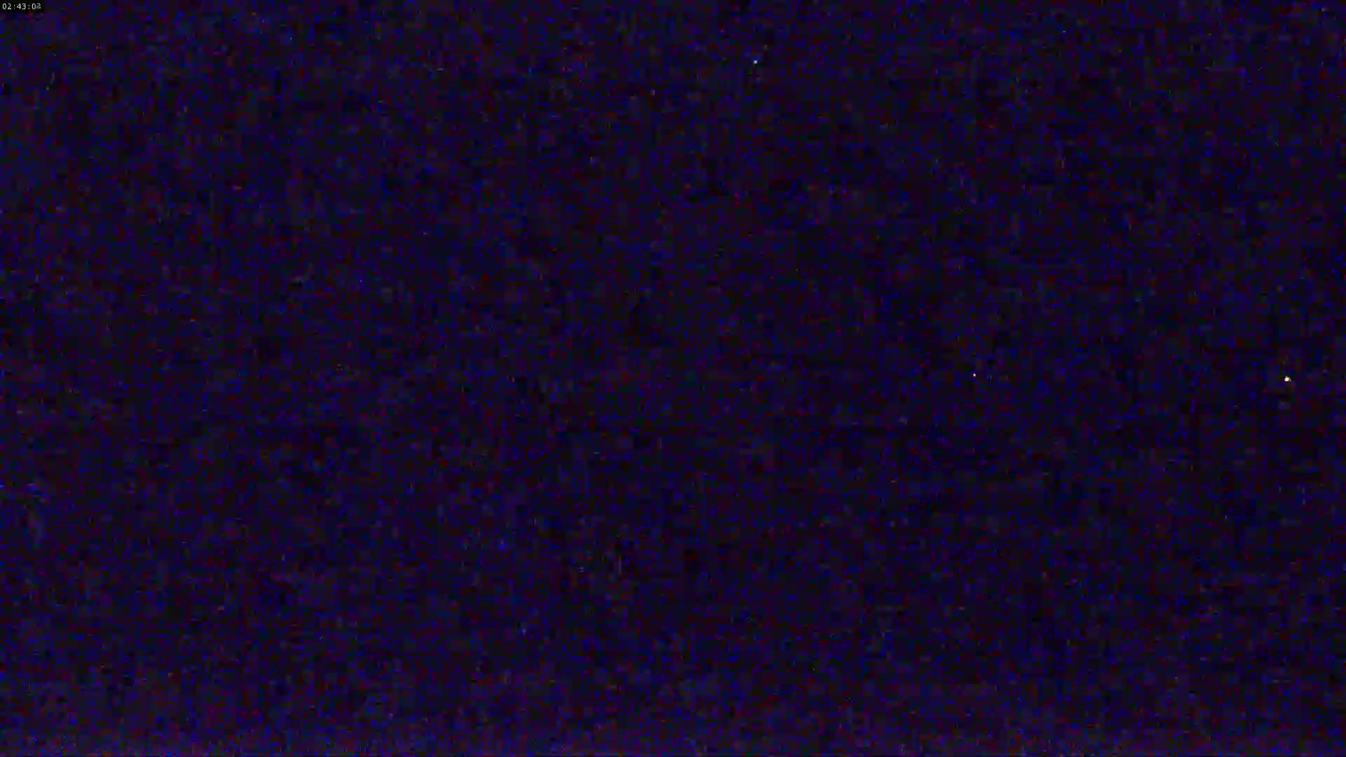 The image shows a dark, grainy, mostly black-blue screen, possibly depicting a night scene with a few faint lights.
