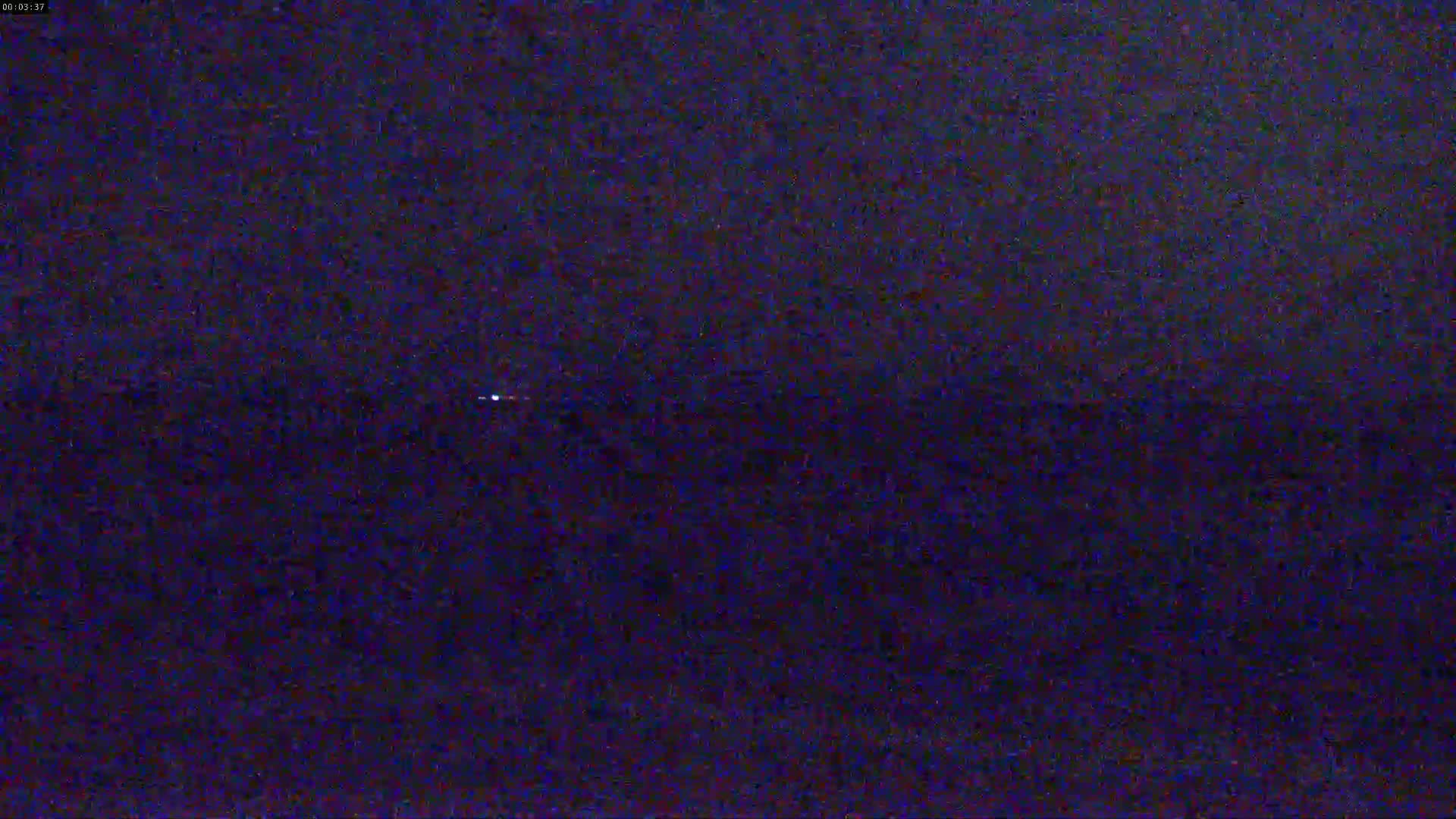 A dark, possibly nighttime, outdoor scene shows a very faint, distant light source.
