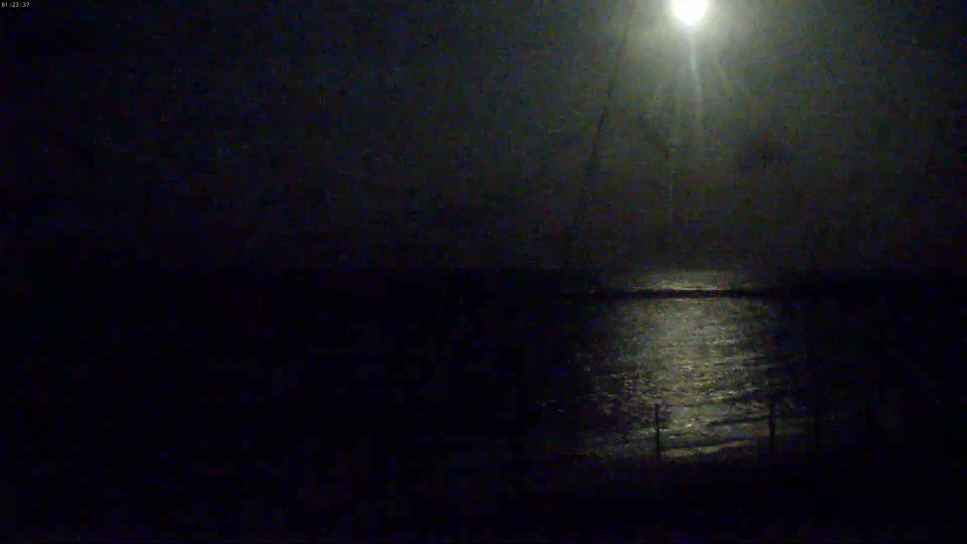 A bright moon shines on dark, gently rippling water at night.