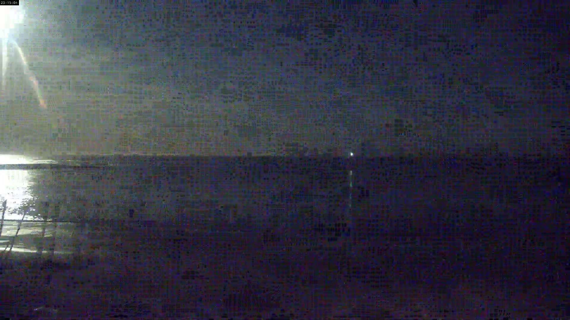 A nighttime, low-light view of a calm body of water under a dark, cloudy sky.