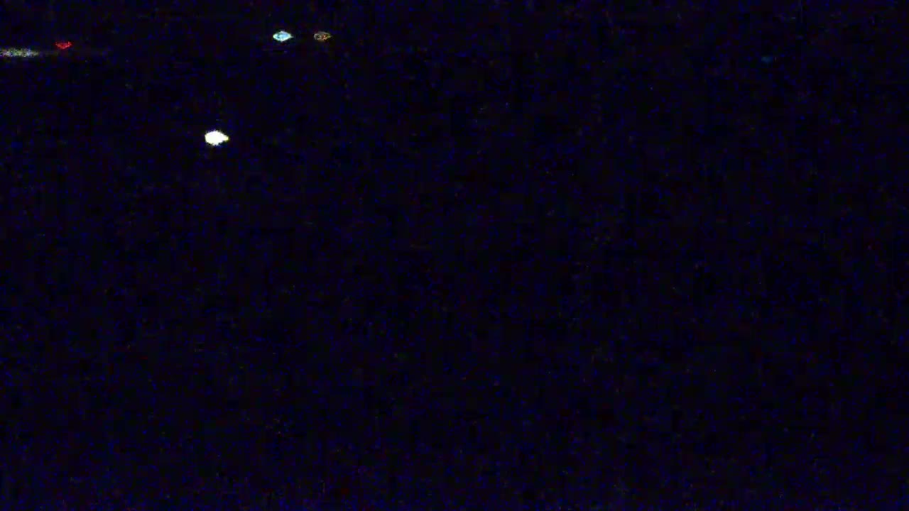 A dark, nighttime scene shows several small, indistinct lights scattered across a black background.