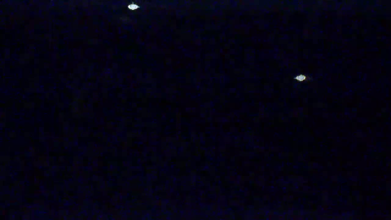 A dark, nighttime scene shows three faint, distant lights against a black sky.