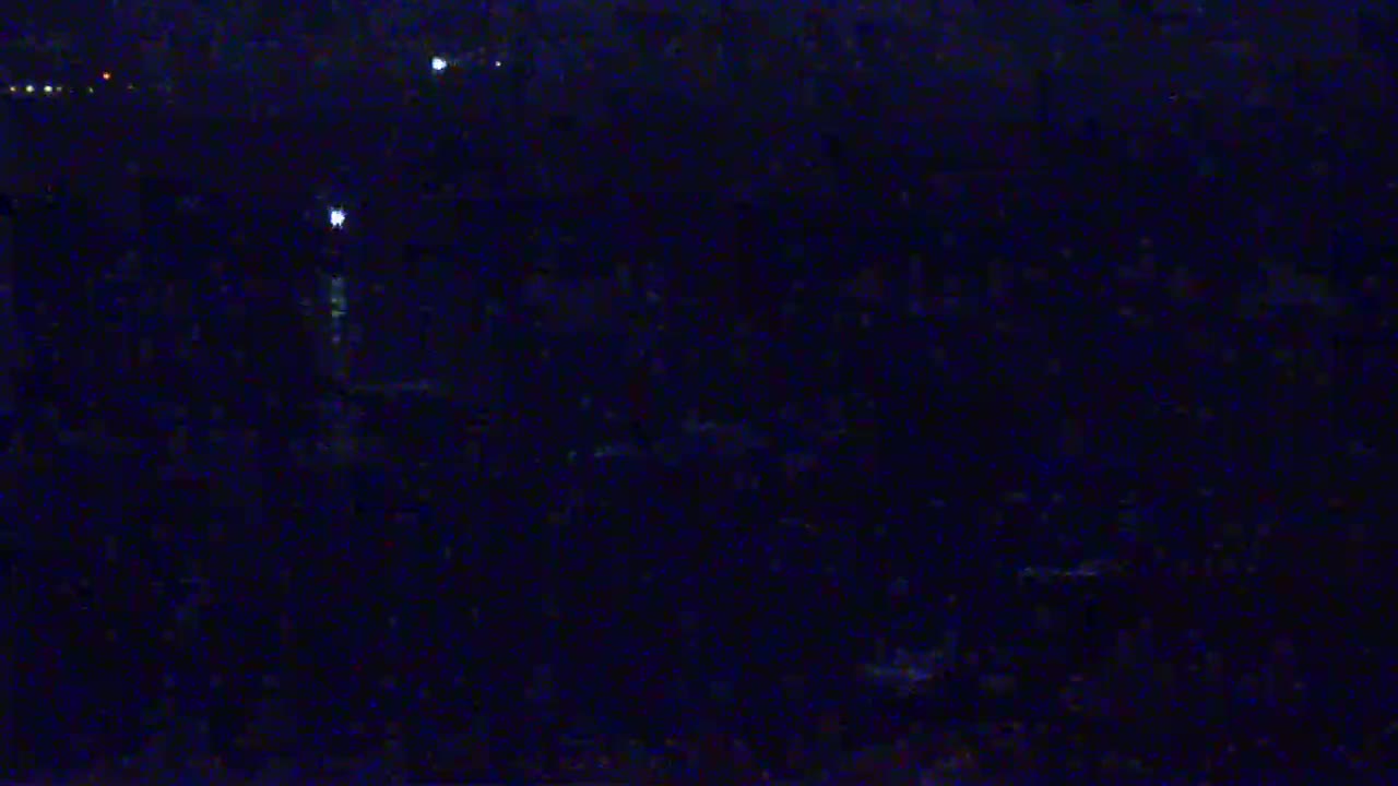 A dark, nighttime scene shows a few faint lights in the distance.