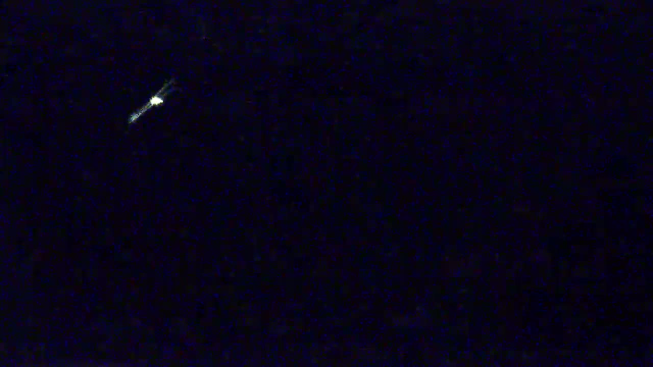 A bright streak of light appears to be moving across a dark, nighttime sky.