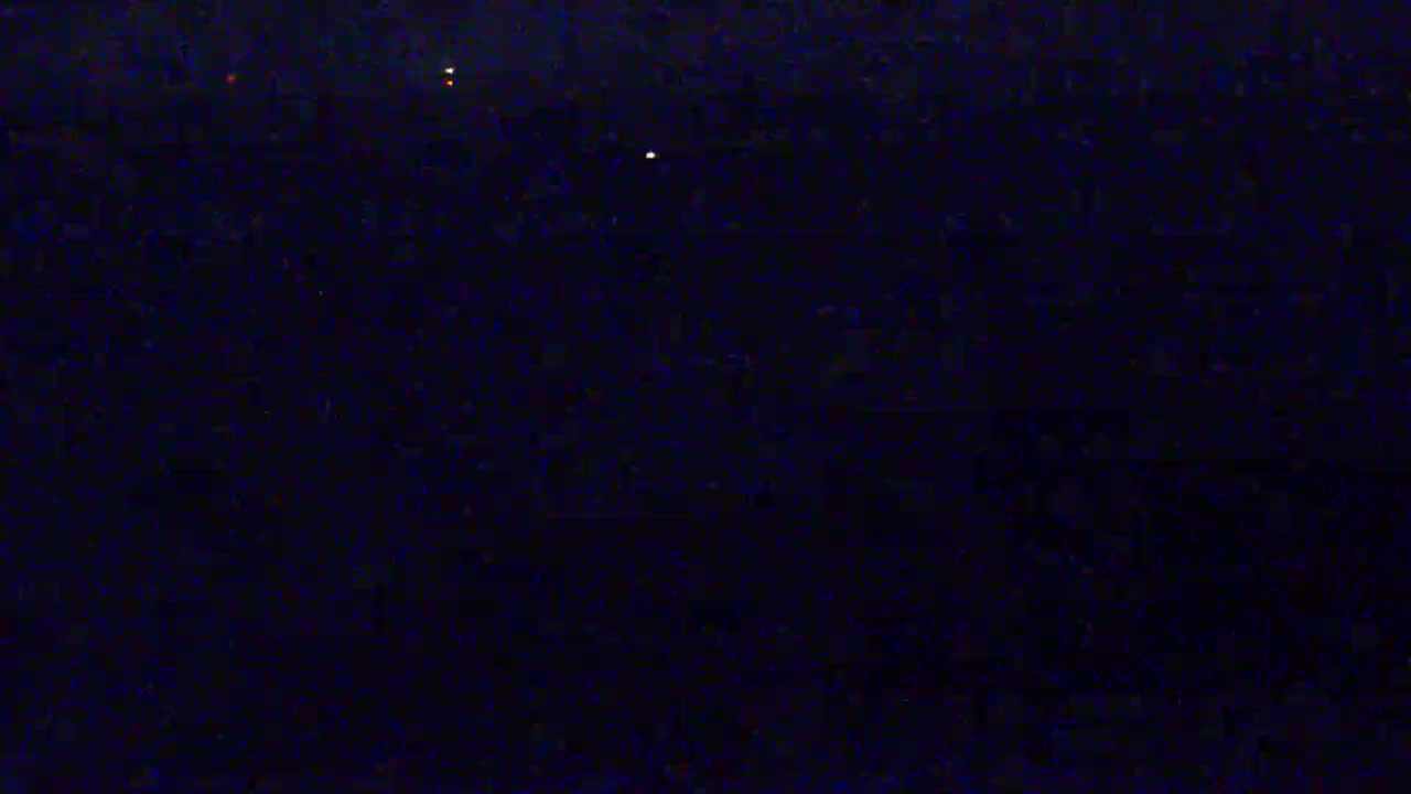 A dark, possibly nighttime scene shows a few faint, distant lights against a mostly black background.
