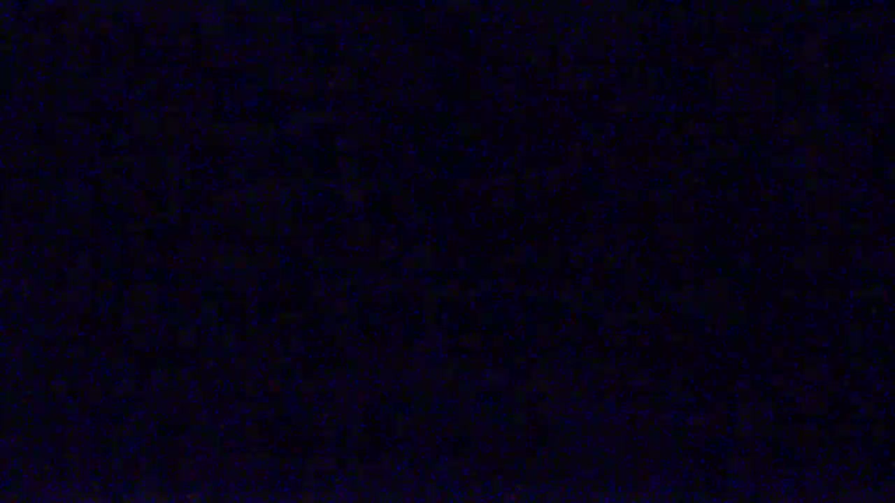 The image shows a dark, mostly black surface with tiny specks of blue scattered across it.