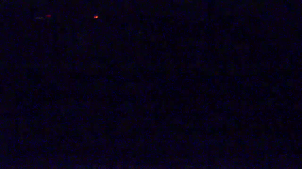 A dark, possibly nighttime scene with a few faint, distant red lights.