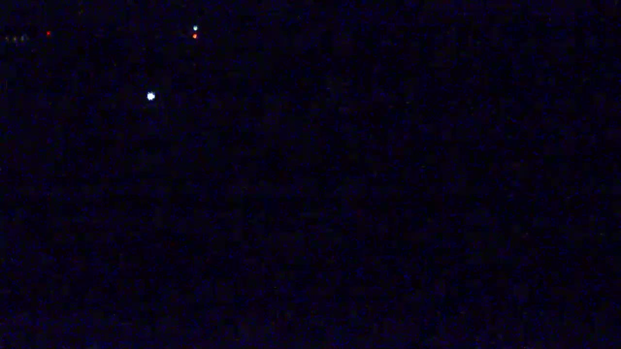 A dark, nighttime scene with a few small, distant lights visible.