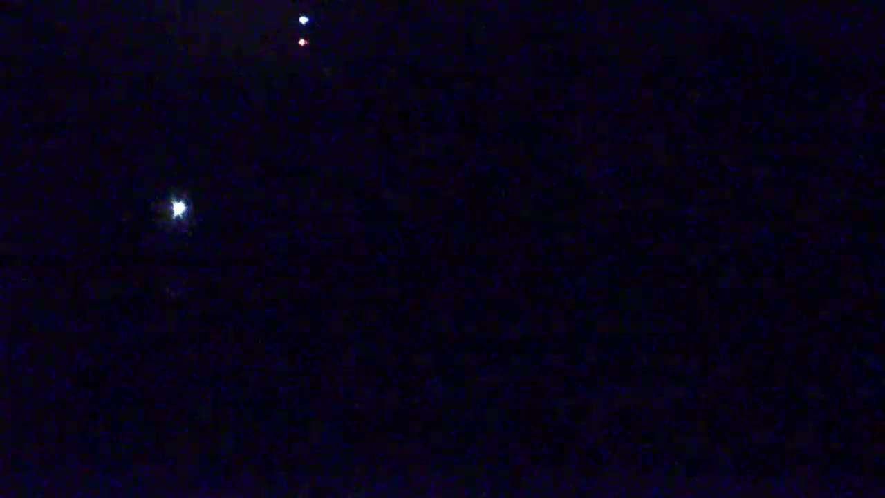 A dark night sky shows a bright star and two fainter, colored lights.