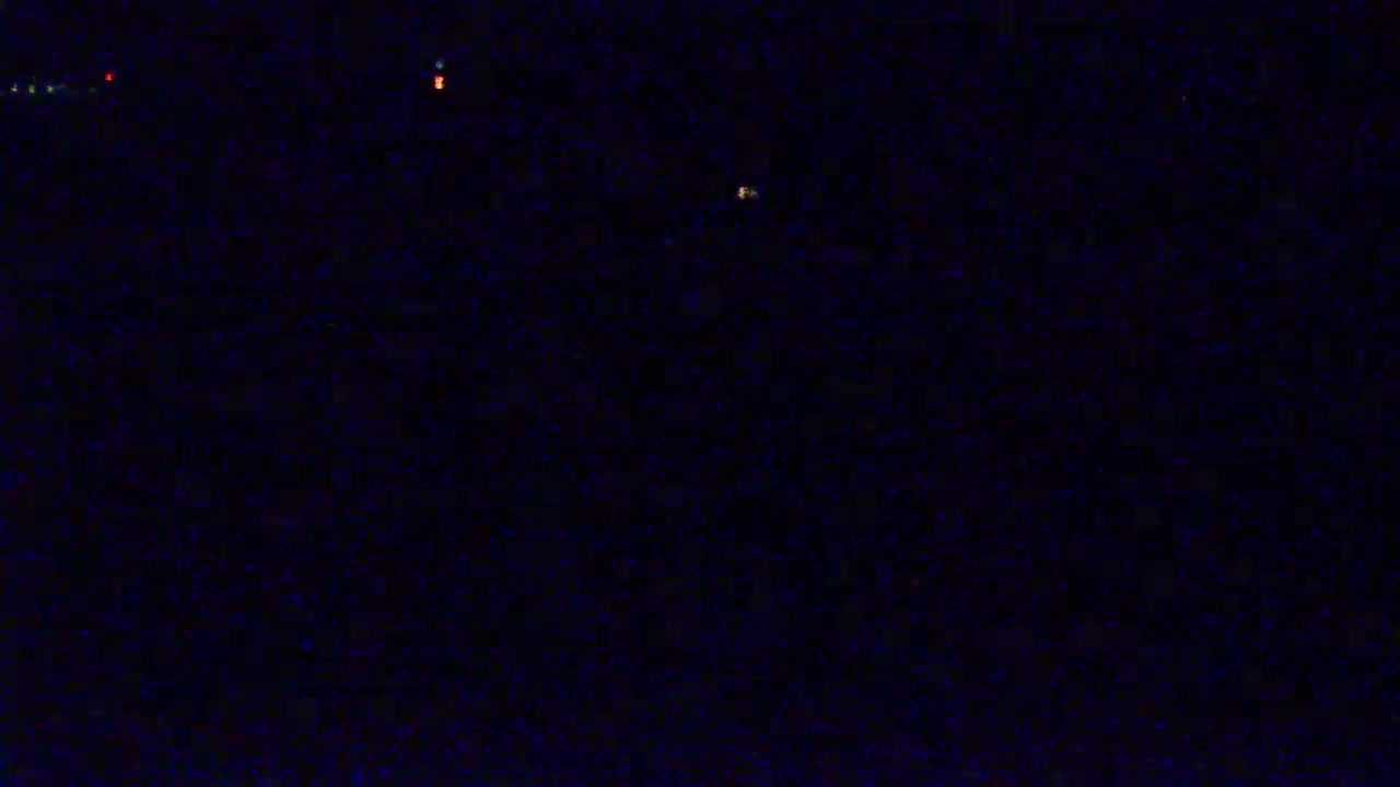 A dark, nighttime scene shows a few small, distant lights.