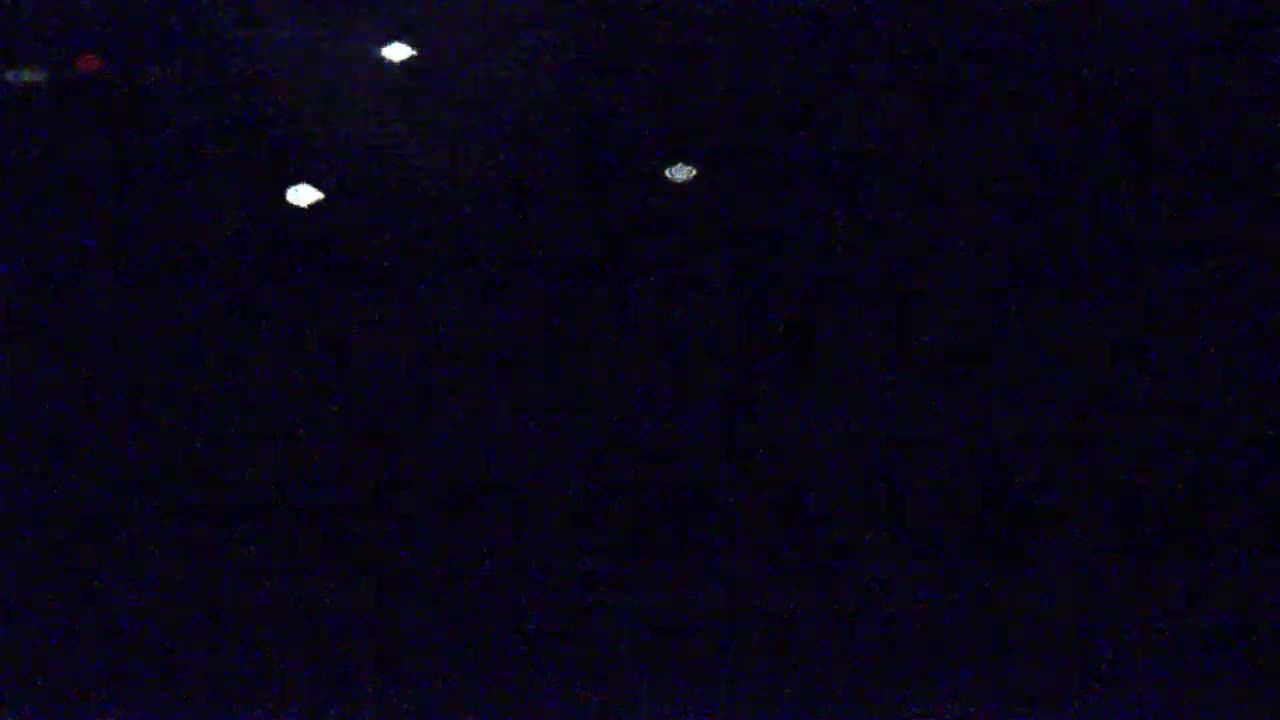 A dark, nighttime scene shows several small, bright lights scattered across a mostly black background.