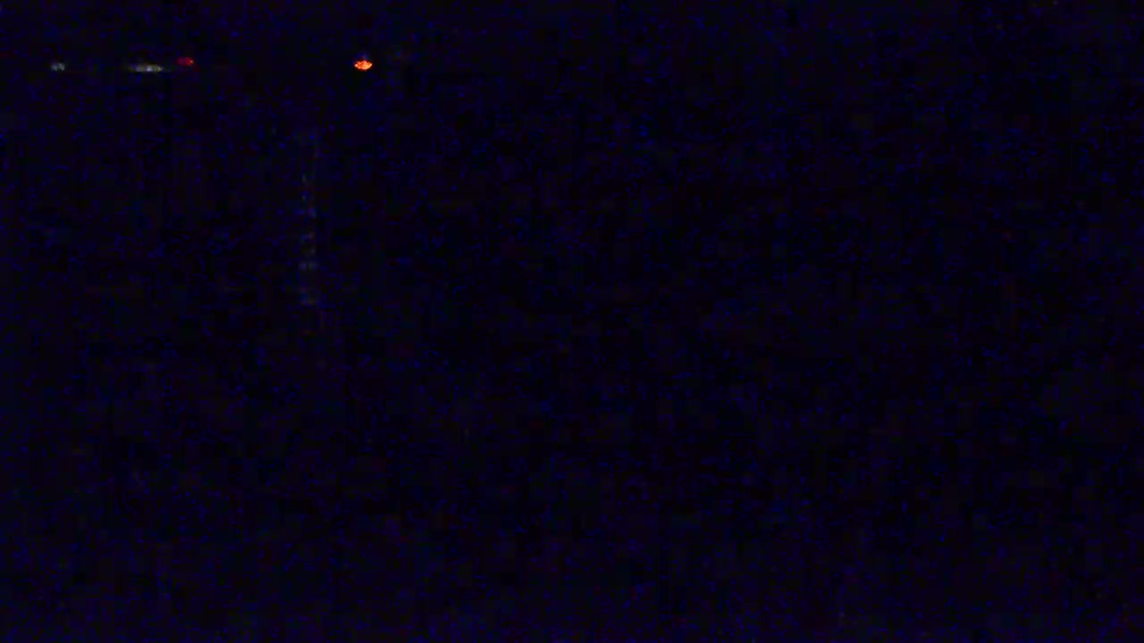 A dark, nighttime scene shows a few faint, distant lights.