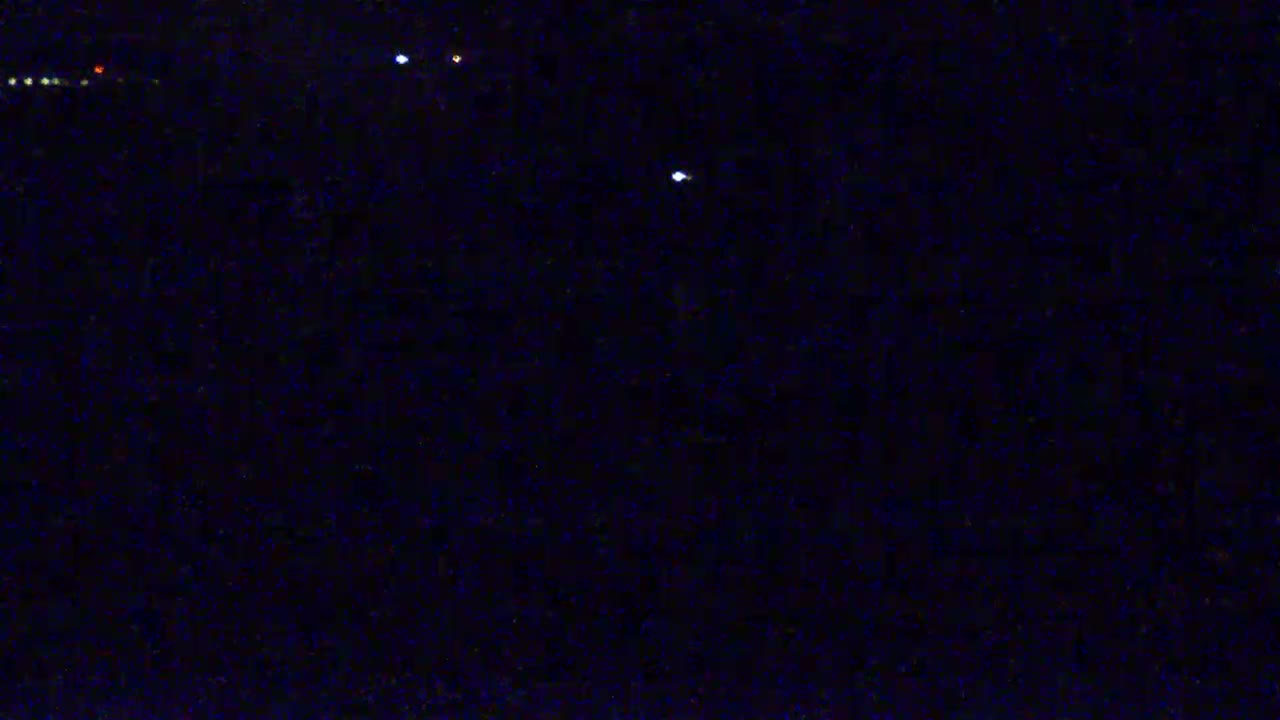 A dark, nighttime scene shows several small, distant lights against a mostly black background.