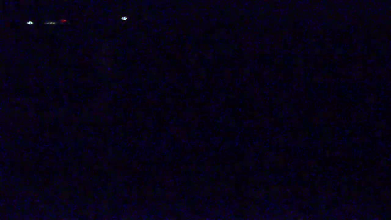 A dark, nighttime scene shows a few distant, small lights.