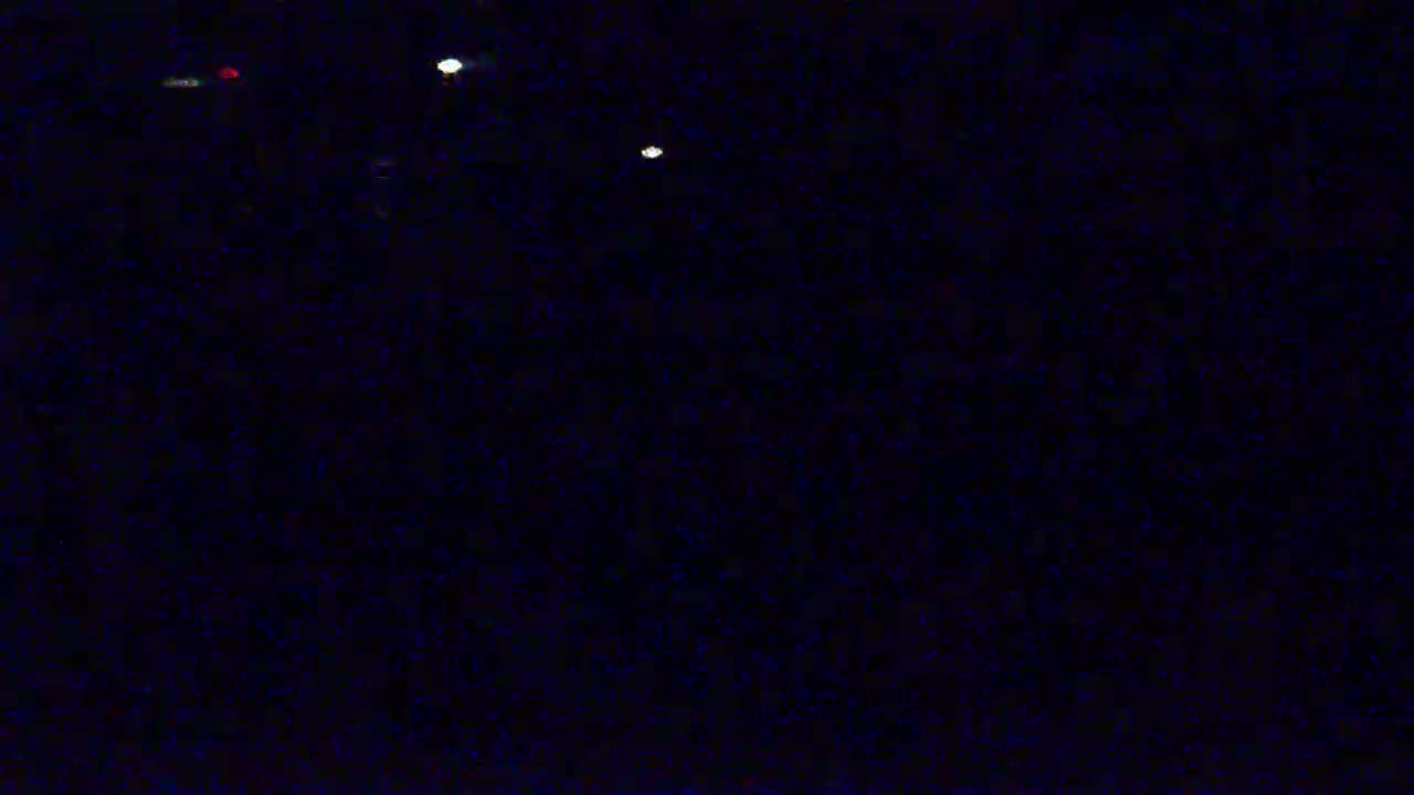 A dark, nighttime scene shows several distant, blurry lights.