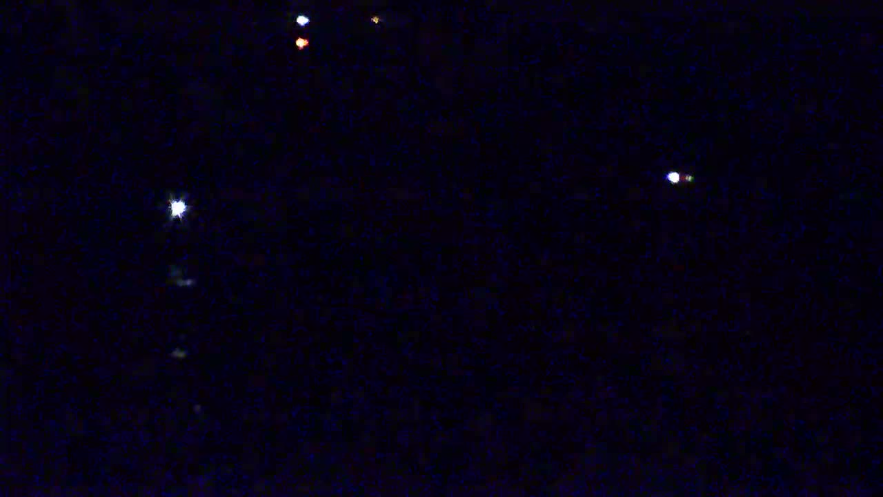 A dark night sky shows several bright lights, some appearing white and others showing hints of color.