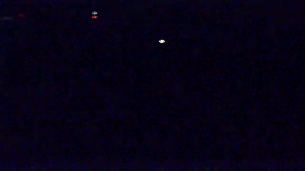 A dark, nighttime scene features a few small, distant lights.