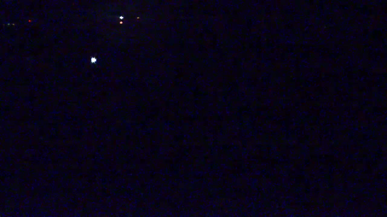 A dark, nighttime scene shows several faint lights in the distance against a mostly black background.