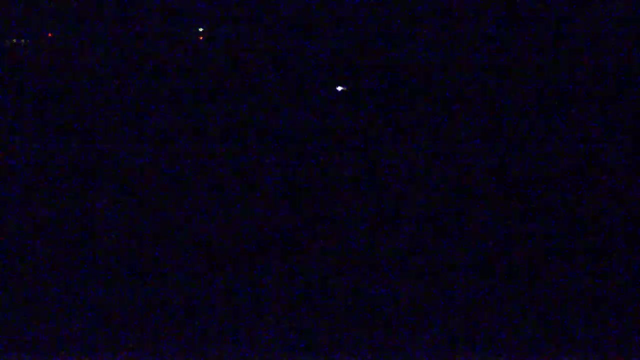 A dark nighttime scene shows several faint lights in the distance.
