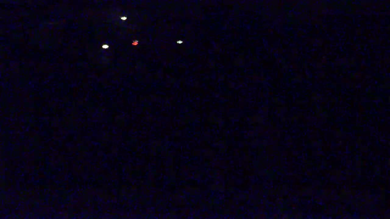 Three white lights and one red light are visible in a dark, nighttime sky.