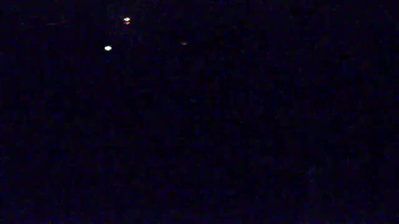 A dark, nighttime scene shows several small, bright lights against a dark, grainy background.