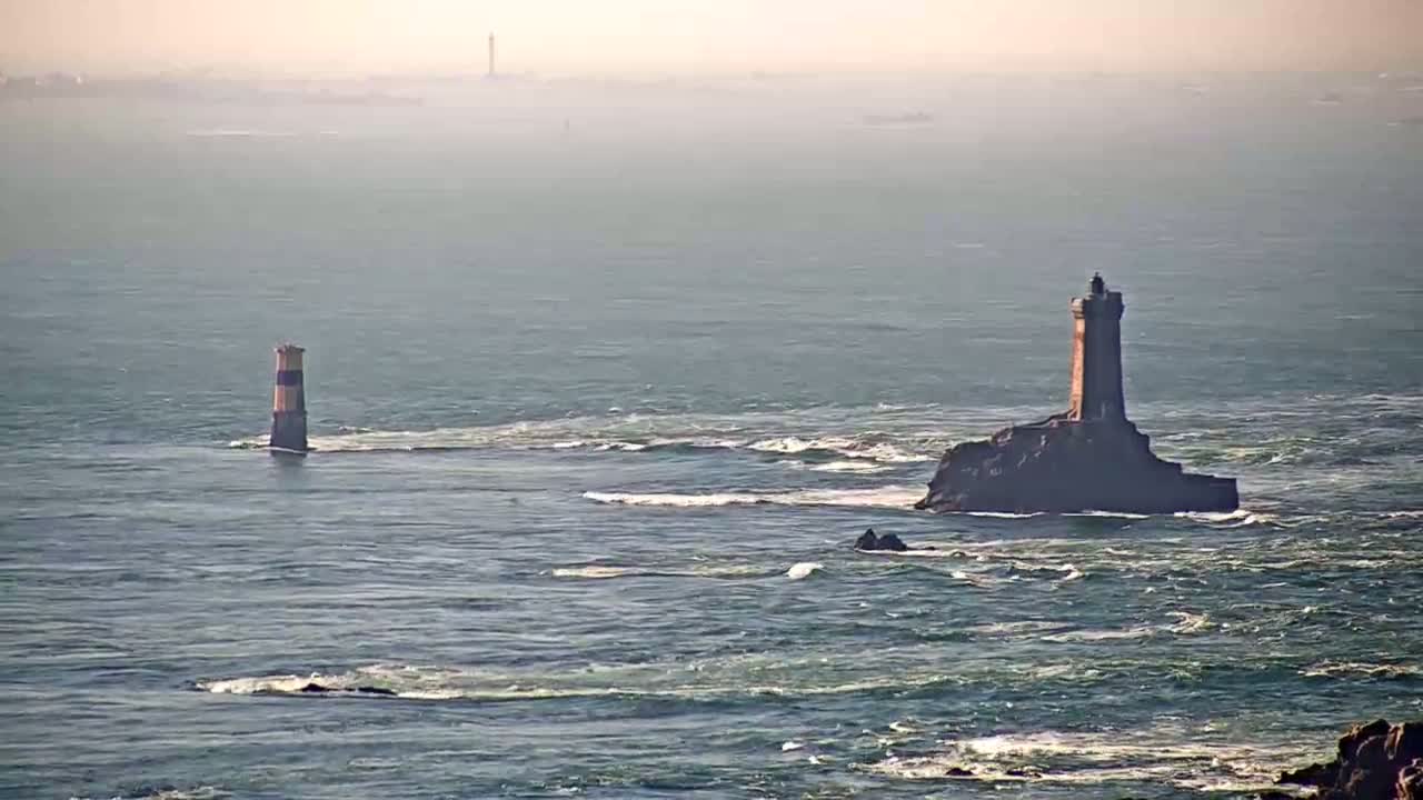 Two lighthouses stand in a hazy, somewhat choppy ocean.