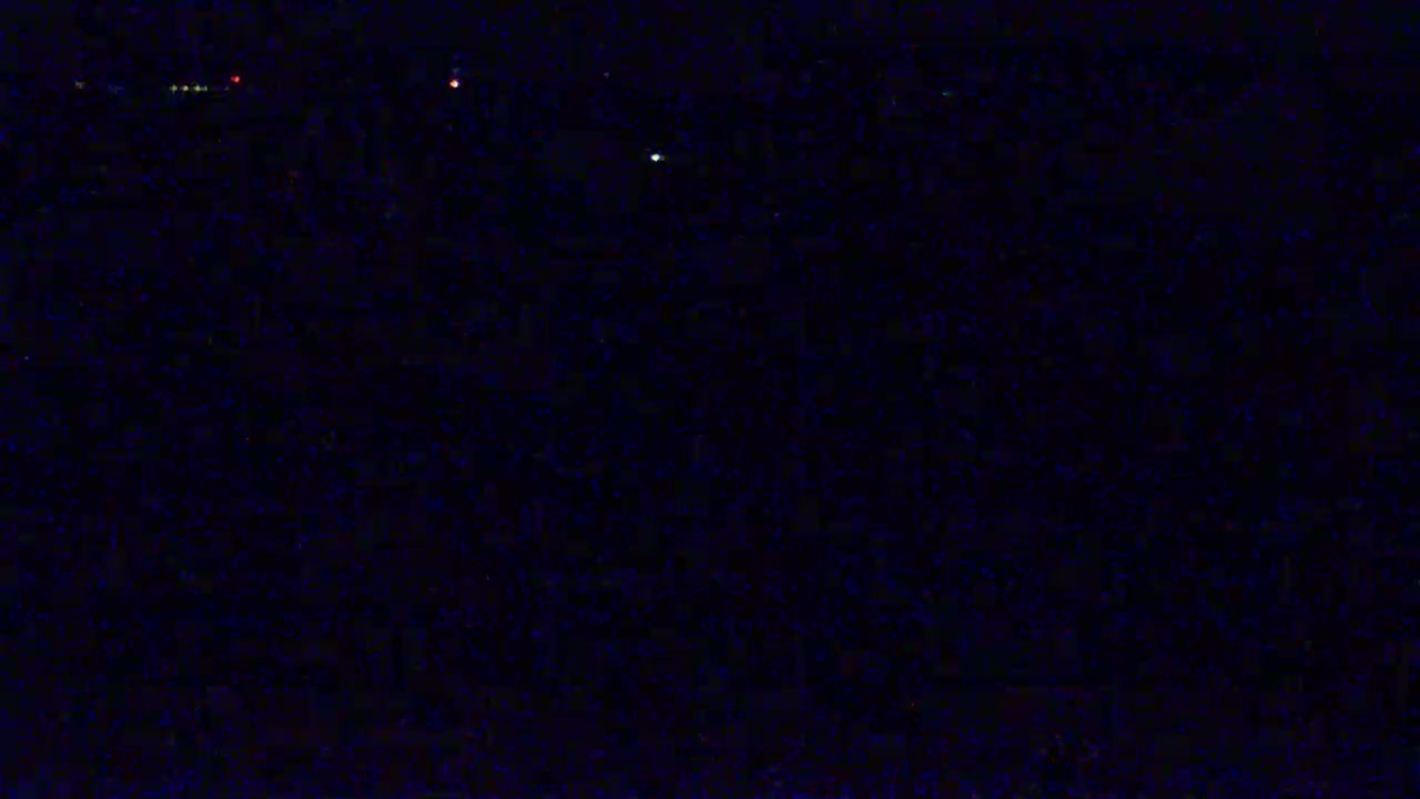 A nighttime view shows a dark expanse speckled with faint, distant lights.