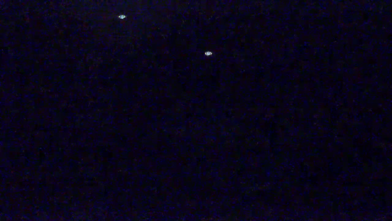 A dark, nighttime scene shows two small, bright lights in the distance.