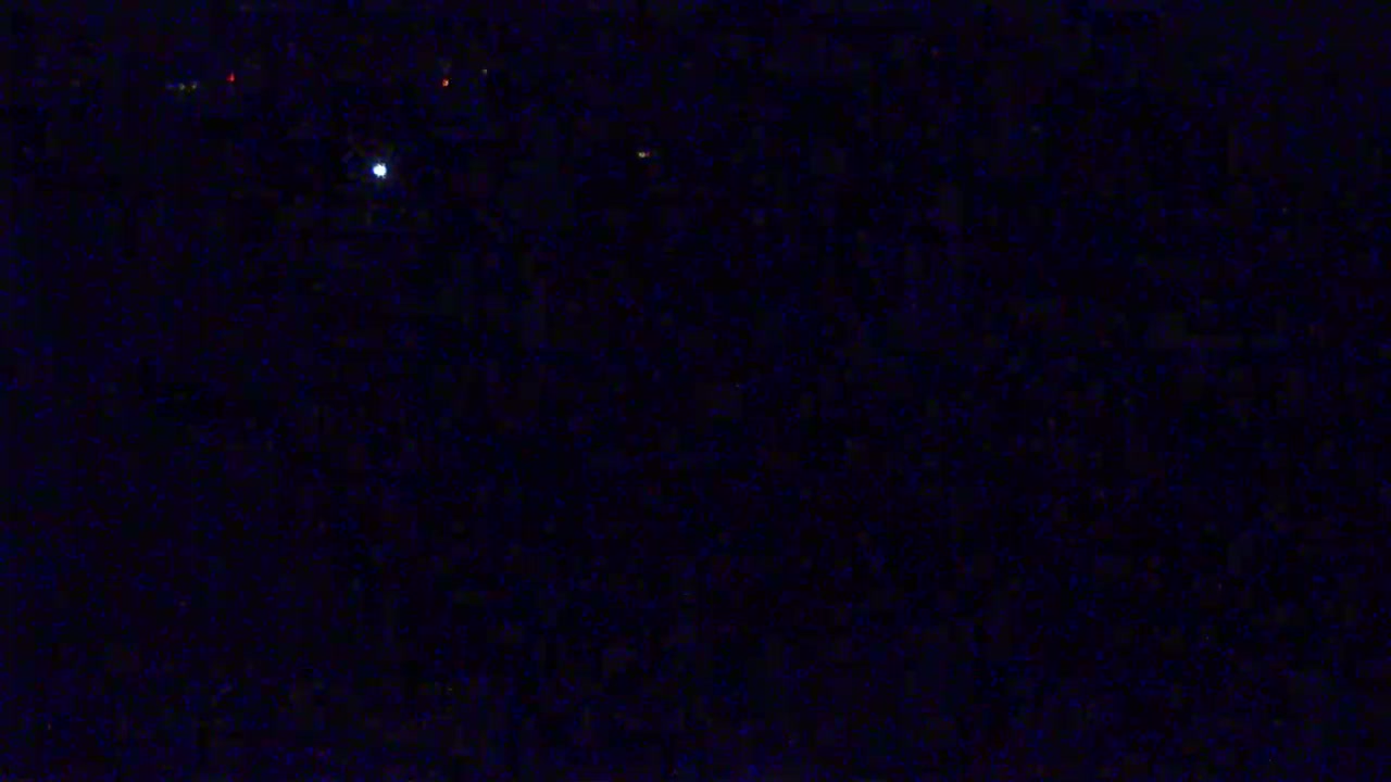 A dark, nighttime scene shows a few faint lights in the distance under a clear, starlit sky.