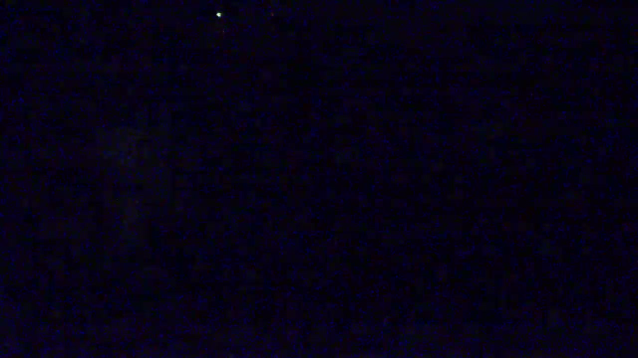 A dark, night scene shows a field of indistinct tiny specks of light against a black background.
