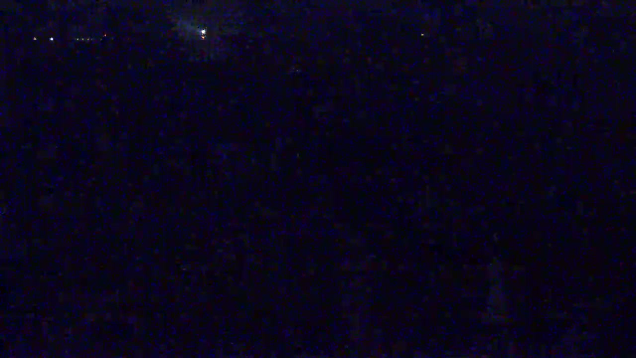 A dark, nighttime scene shows a few distant, faint lights against a mostly black background.