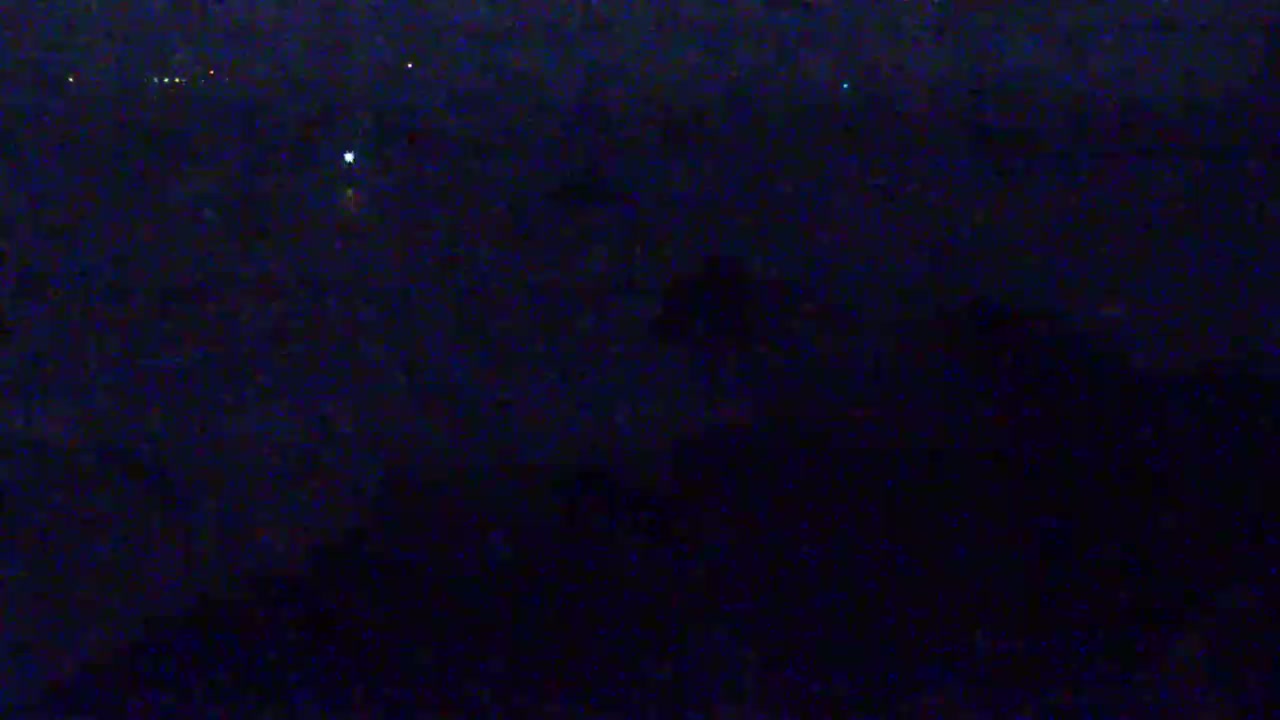 A dark, nighttime scene shows a few distant lights against a very dark background.