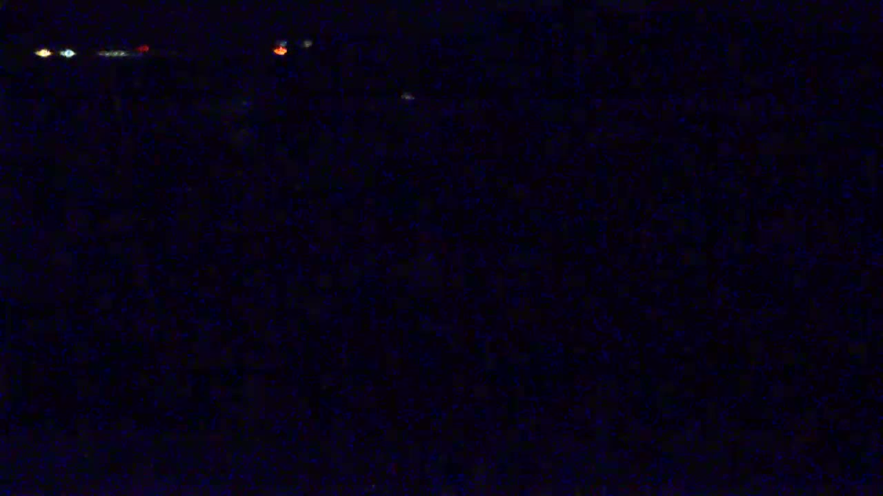 A dark, nighttime scene shows a few distant, blurry lights.