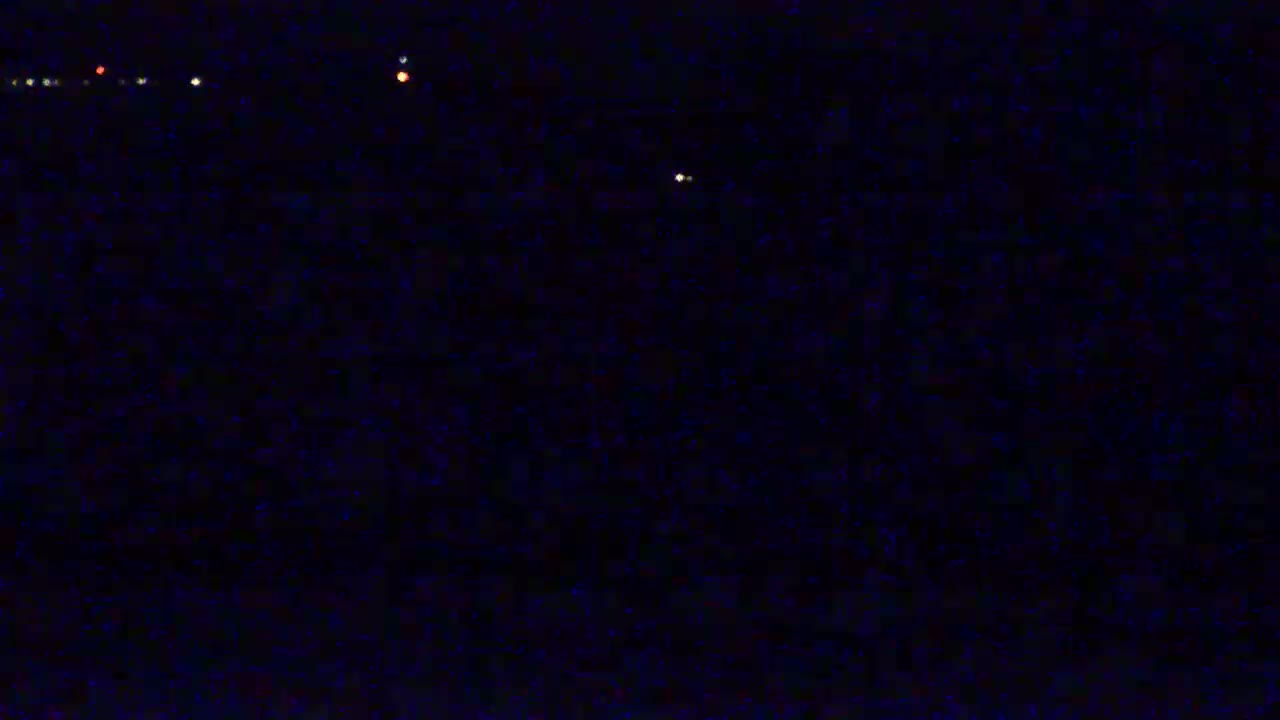 A nighttime image shows a dark, possibly stormy, sky with several small, distant lights visible.