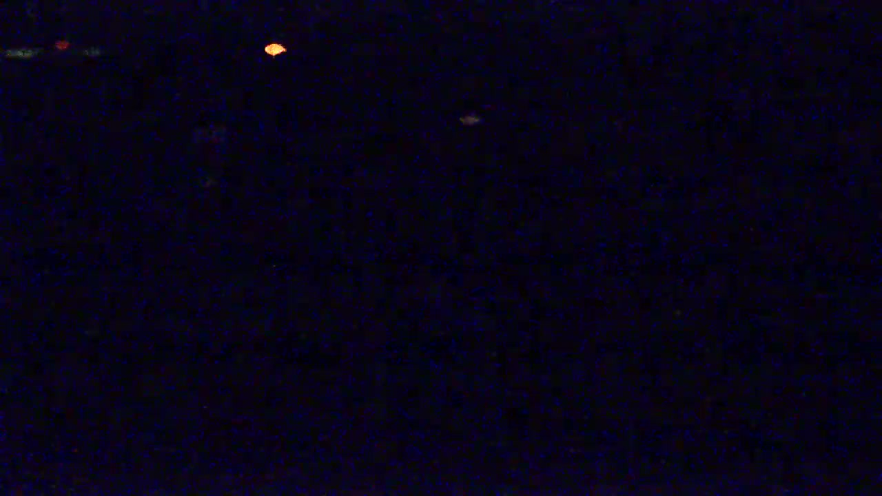 A dark, nighttime scene with a few faint, distant lights visible.
