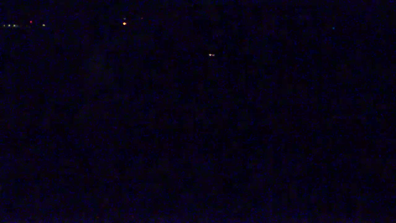 A dark, nighttime scene shows a few distant lights.
