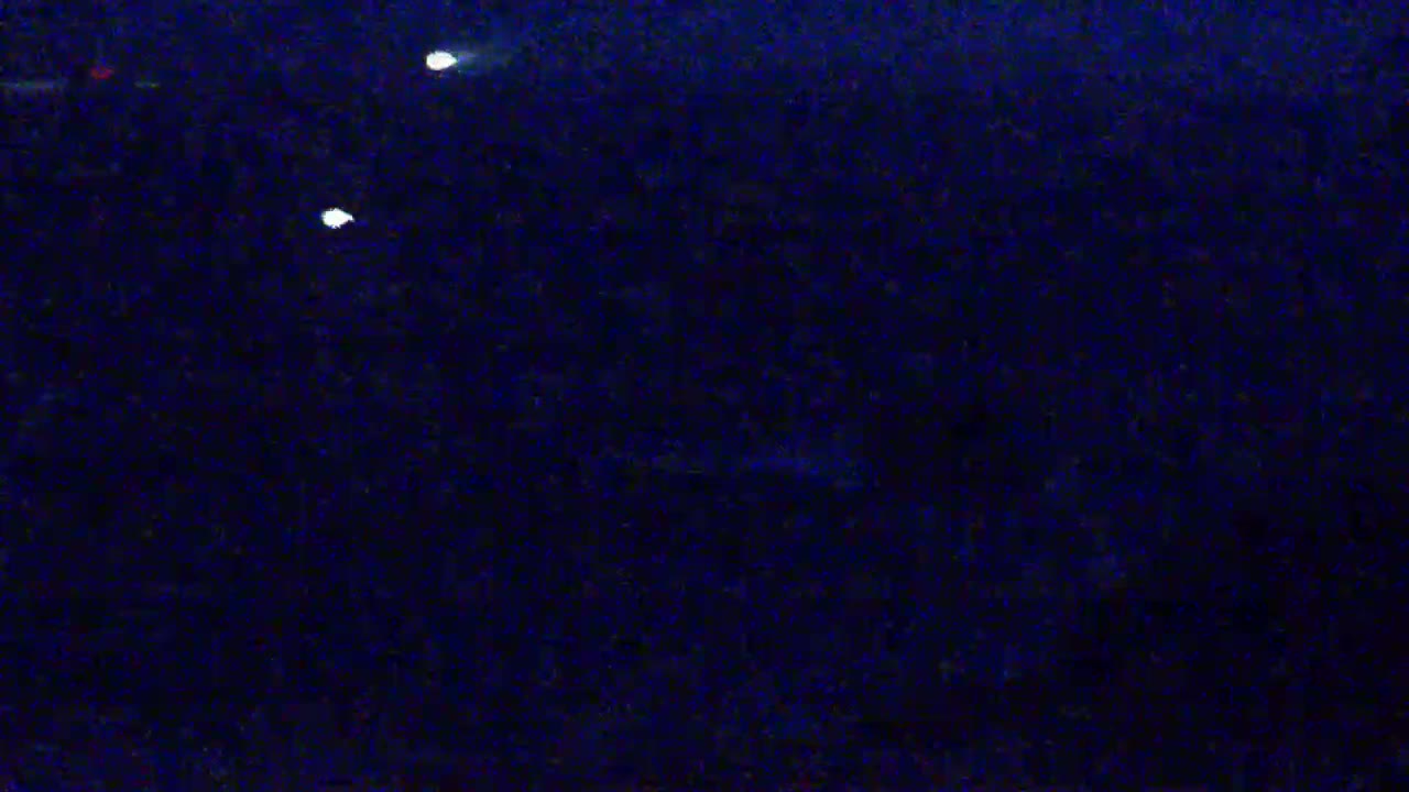 A dark, nighttime scene features three small, bright lights in the distance.