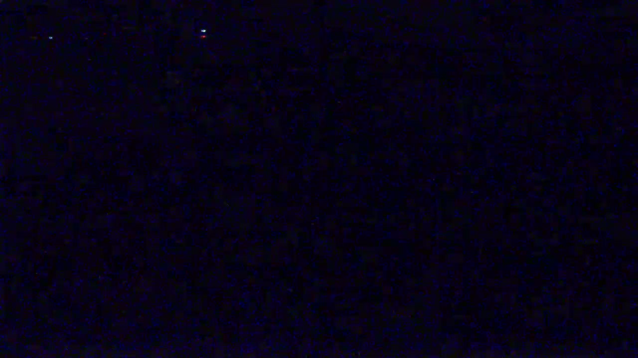 A dark, mostly black image with a few tiny specks of light.
