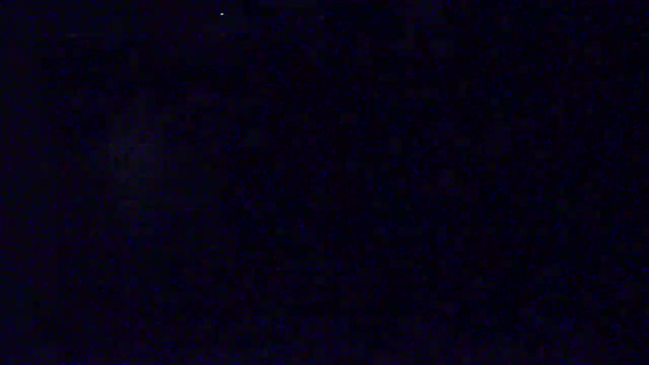 A dark, mostly black image with small specks of blue scattered throughout.