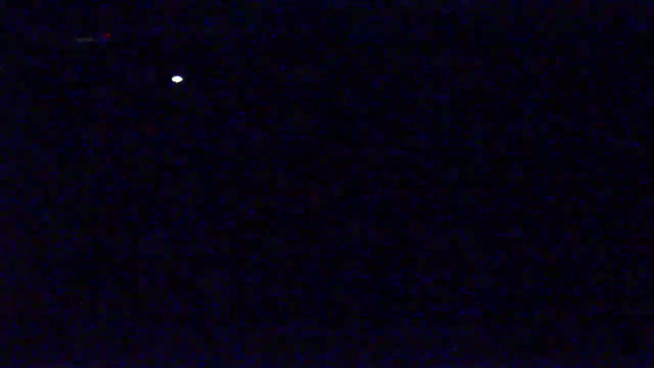 A single bright light is visible in a dark, nighttime sky.