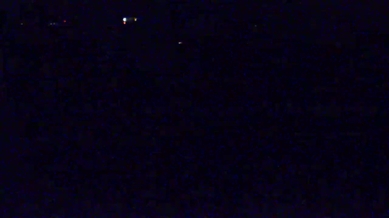 A dark, nighttime scene shows a few distant, faint lights in an otherwise black expanse.