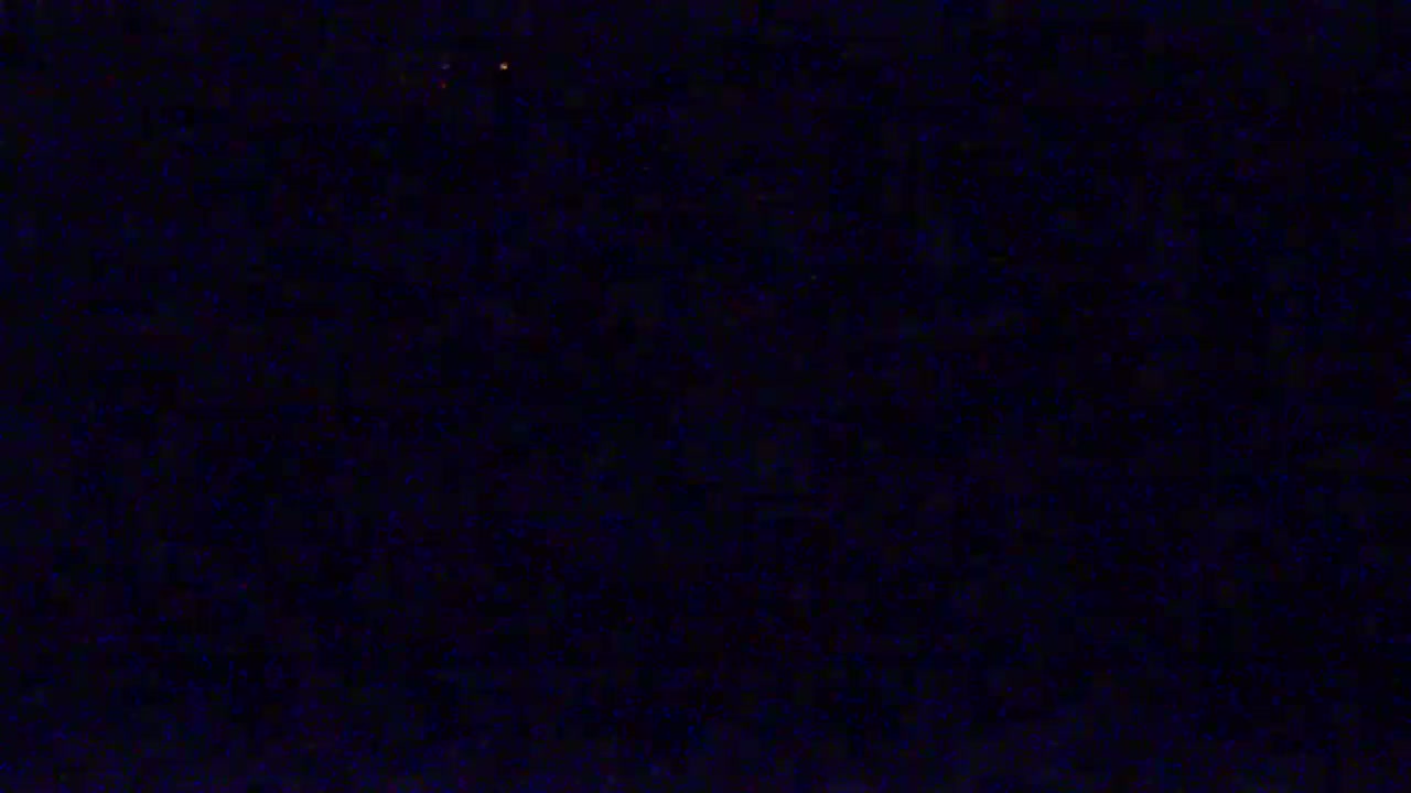 The image shows a dark, possibly nighttime scene with a few faint orange lights in the distance.
